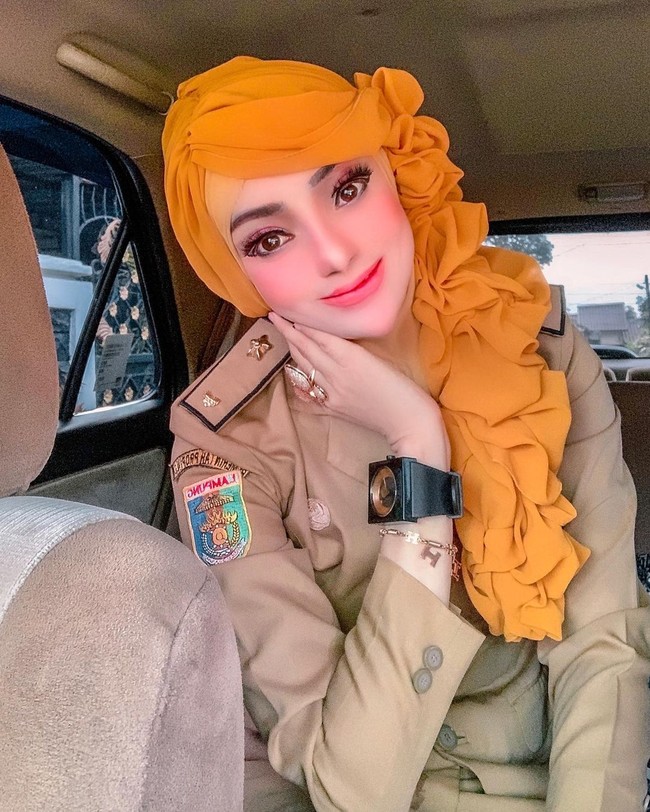 Berawal dari video yang diunggah oleh akun TikTok @yuni_jasminebutiq. Ia tampak memakai seragam PNS dan berpose memperlihatkan gaya hijab kuning menyerupai rambut. Wanita itu juga berdandan dengan riasan full makeup, bulu mata tebal dan blush on. Penampilannya ini pun langsung menuai kritikan karena dianggap berlebihan. Foto: Instagram @yuni_jasminebutiq.