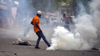 Bukannya menghindar, seorang demonstran justru menendang tabung gas air mata yang ditembakkan polisi.