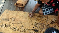 Ray Robert Ongge (21) melukis dengan perlahan di atas selembar kulit kayu dengan lebar 70 x 60 centimeter.