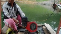 Pak Mugi sedang menjalankan kapal motornya