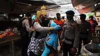 Polisi berkostum wayang memberikan contoh pemakaian masker yang benar.