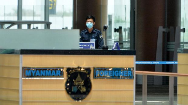 An airport worker wearing a facemask looks on as members of Myanmar's military spray disinfectant as a preventive measure to contain the spread of COVID-19 coronavirus at Naypyidaw International Airport in Naypyidaw on March 31, 2020. (Photo by Thet Aung / AFP)