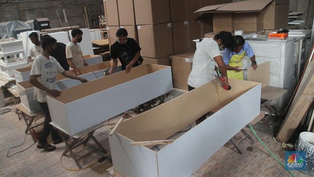 Pekerja menyelesaikan pembuatan peti khusus jenazah COVID-19 di Funisia Perkasa, Kota Tangerang, Banten, Rabu (3/2/2021). Pabrik furnitur tersebut kini memproduksi peti untuk jenazah COVID-19 dan bisa menghasilkan 50 hingga 100 buah peti per harinya. Lonjakan kasus Covid-19 berdampak pada permintaan peti mati. (CNBC Indonesia/ Muhammad Sabki)