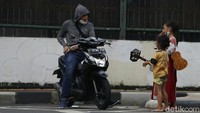 Sejumlah anak pengamen jalanan dengan membawa gitar kecil, tengah mengamen di kawasan lampu merah.