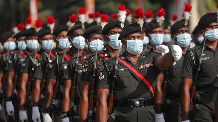 Sri Lanka Independence A Sri Lankan police officer walks crosses a road as special force soldiers ride motorbikes during 73rd Independence Day parade rehearsal with a calf elephant in Colombo, Sri Lanka, Wednesday, Feb. 3, 2021. Sri Lanka's independence from British colonial rule is celebrated on Feb. 4 each year. (AP Photo/Eranga Jayawardena)