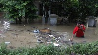 Warga melintasi banjir yang menggenangi permukiman di Kampung Sewu, Jebres, Solo Jawa Tengah, Kamis (4/2/2021).
