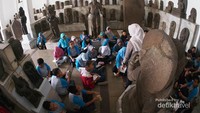 Anak sekolah mendengarkan penjelasan dari pemandu wisata