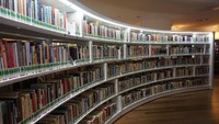 Koleksi buku yang tersusun apik pada rak buku yang unik