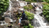Pengunjung menikmati air terjun dengan mandi langsung dibawah aliran air.