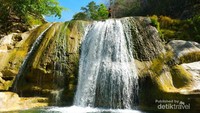 Air terjun mengalir dari tebing yang rendah.