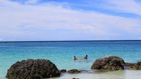 Wisatawan sedang berenang di air yang biru