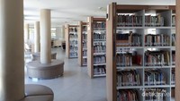 Deretan rak buku dan sofa yang melingkar di tiang-tiang ruangan perpustakaan