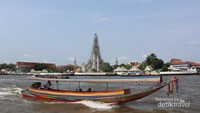 Sebuah kapal melintas dengan latar Wat Arun