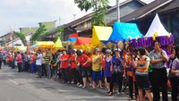 Masyarakat berdiri sambil memegang dupa menunggu arak-arakan tongkang