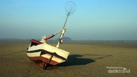 Perahu nelayan di tepi pantai yang sedang surut