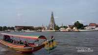 Perahu yang lalu lalang dengan latar Wat Arun di Thailand