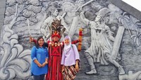 Berfoto dengan latar relief yang menggambarkan perang Tondano .