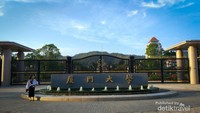 Gerbang kampus Xiamen University dengan pegunungan di kejauhan sebagai backgroundnya