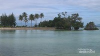 Pantai yang tenang dengan air laut yang tampak biru dan jernih