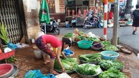 Pedagang sayur mulai menggelar dagangannya di trotoar kota Can Tho.