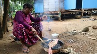Sang Ibu membakar ikan untuk hidangan para tamu