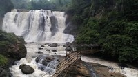 Jembatan di tengah sungai di depan air terjun