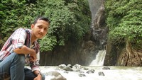 Berfoto di depan air terjun