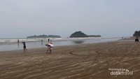 Suasana pantai yang cukup luas dengan ombaknya yang tenang dan pulau yang dapat diseberangi nampak di kejauhan.