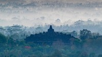 Tampak dari jauh Candi Borobudur diantara pepohanan dan embun pagi.