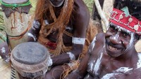 Pak Barnabas tersenyum sembari memamerkan tifa kebanggaannya sehabis mengiringi tari semut para perempuan Kamoro