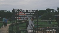 Berfoto di depan papan tanda masuk.