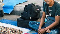 Penjual batu akik menunggu orang membeli dagangannya