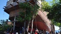 Para warga bersama mengangkat ekor kapal memakai dongkrak