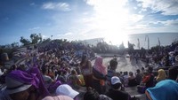 Terik sinar matahari membuat semua penonton harus berusaha menutupi wajah dengan payung, topi, dan kain.