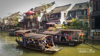 Pemandangan kapal-kapal tua berlayar dengan background rumah-rumah tradisional cina