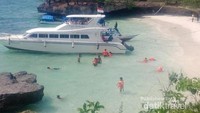 Dari atas bukit dengan latar laut biru serta pasir putih