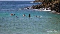 Para pengunjung yang menikmati birunya air laut.