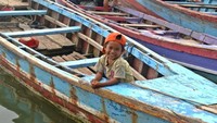 Senyum anak kecil yang sedang memancing di tepi Pulau Pasaran