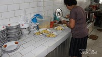 Penjaga warung sedang mempersiapkan beberapa porsi mie