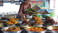 Seorang penjual Nasi Kapau sedang mengambil lauk pauk