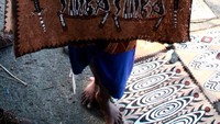Wanita suku sentani yang menjajakan lukisan kulit pohon