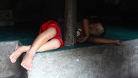 anak penjual suvenir yang tidur di lantai rumah yan dilapisi tai kerbau.jpg