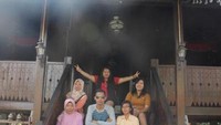 Berfoto di bagian tangga rumah adat.