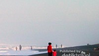 Seorang ibu dan anaknya bermain di pinggir pantai