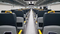 Deretan kursi di gerbong kereta bandara dengan kompartemen di atasnya