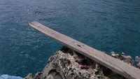 Kayu tempat pelancong loncat untuk berenang di pantai