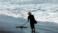 Seorang Petani garam melintasi pantai petanahan
