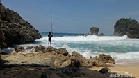 pemancing asik beradu dengan ombak