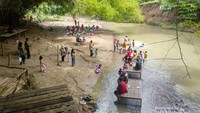 Pengunjung menikmati makanan dan anak-anak bermain di pinggir Kali Gawe