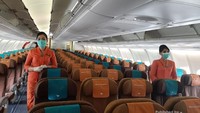 Pramugari menerapkan protokol kesehatan di dalam pesawat